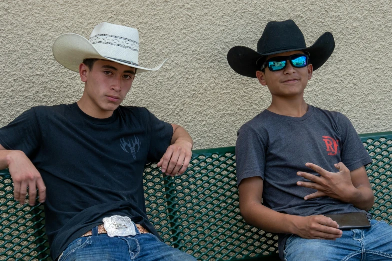 two young men, one wearing sunglasses, the other wearing cowboy hats