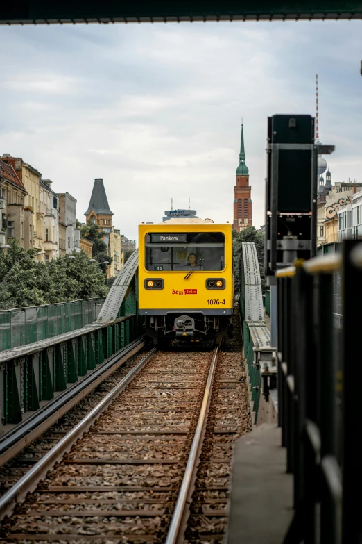 the yellow train is traveling on the tracks