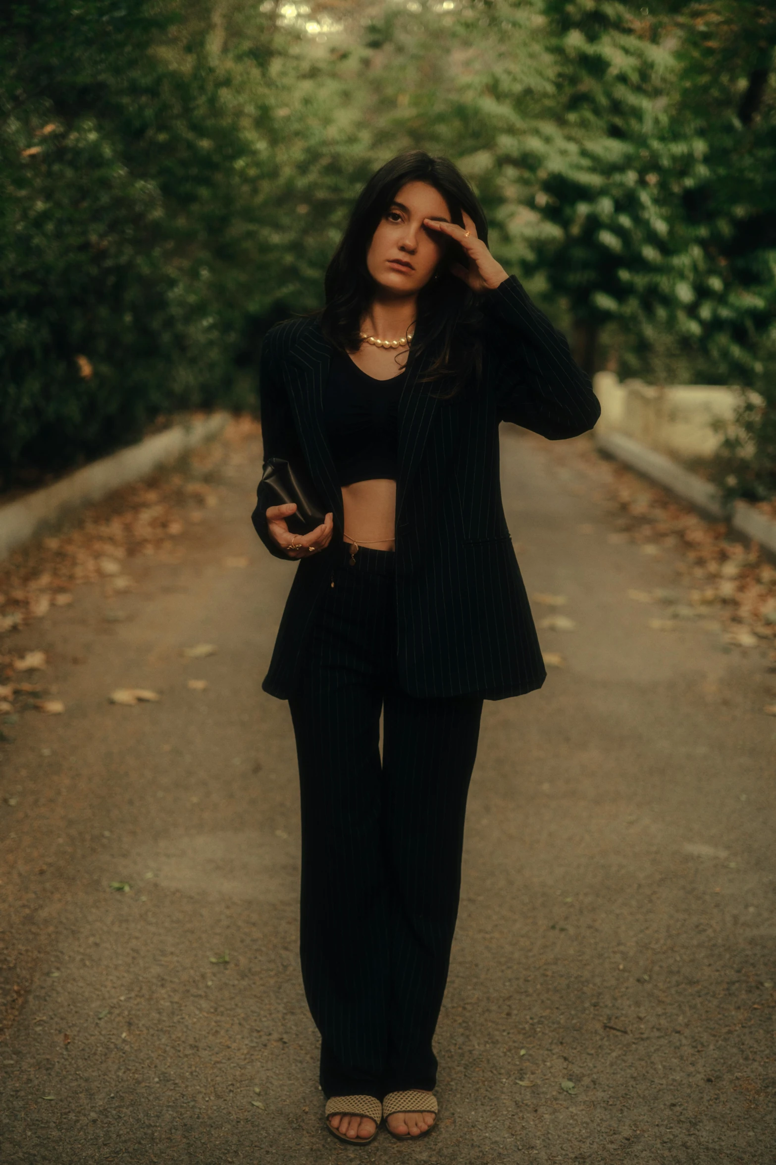 woman standing on a road with her hands near her eyes