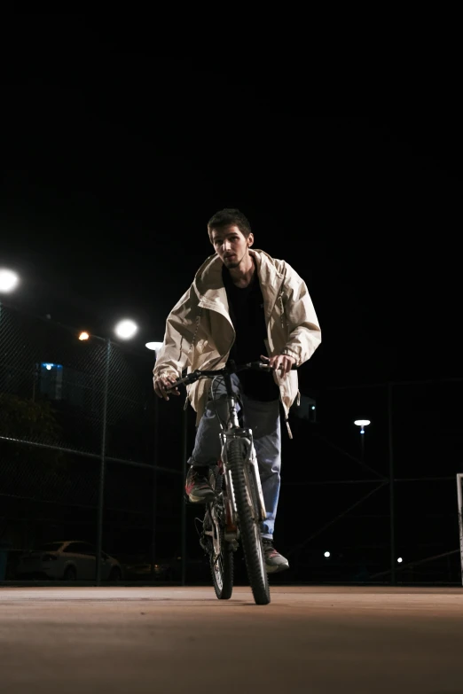 a man riding on the back of a bicycle at night