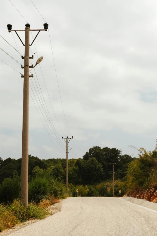 an old telephone pole sits beside a dirt road