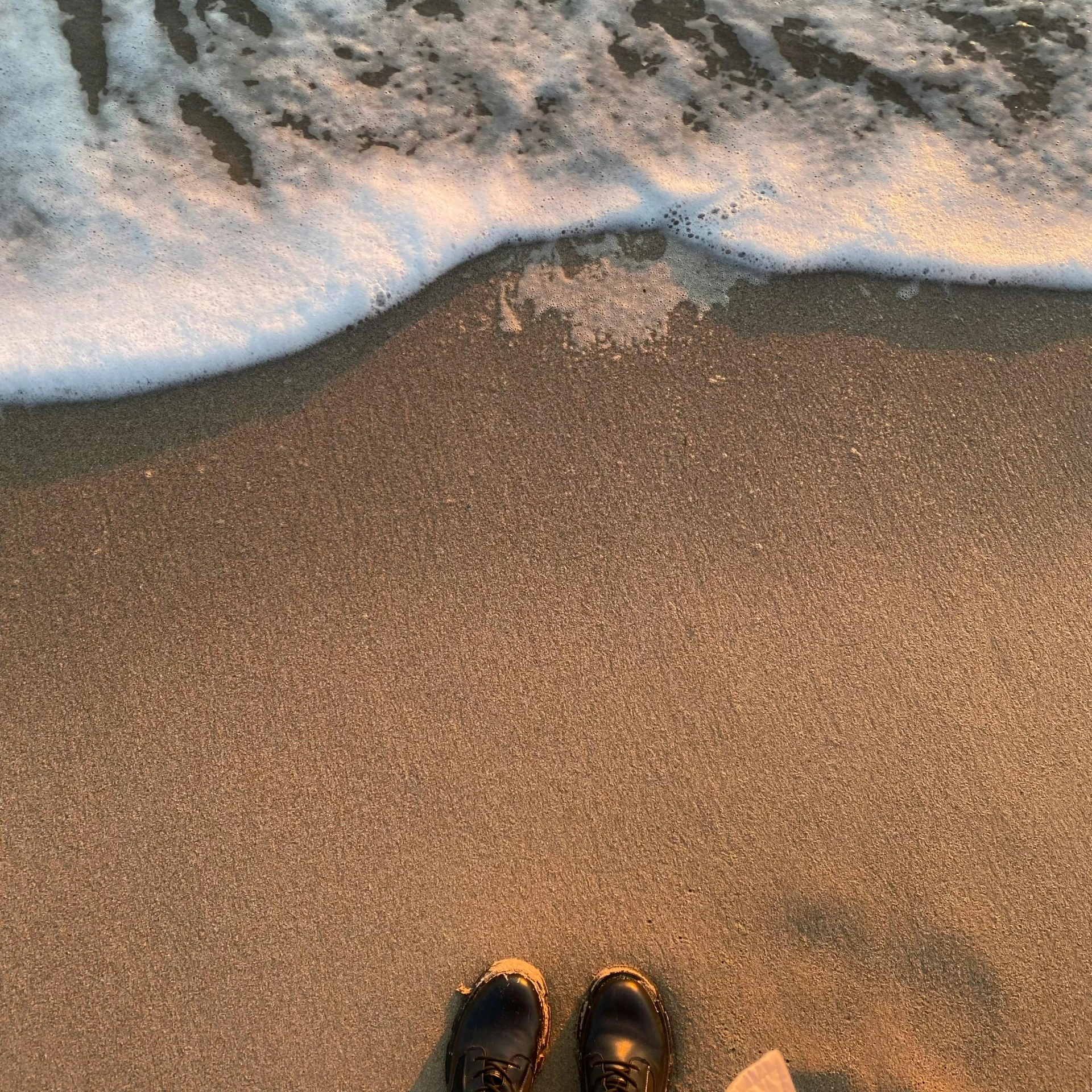 a pair of shoes is placed next to an ocean wave