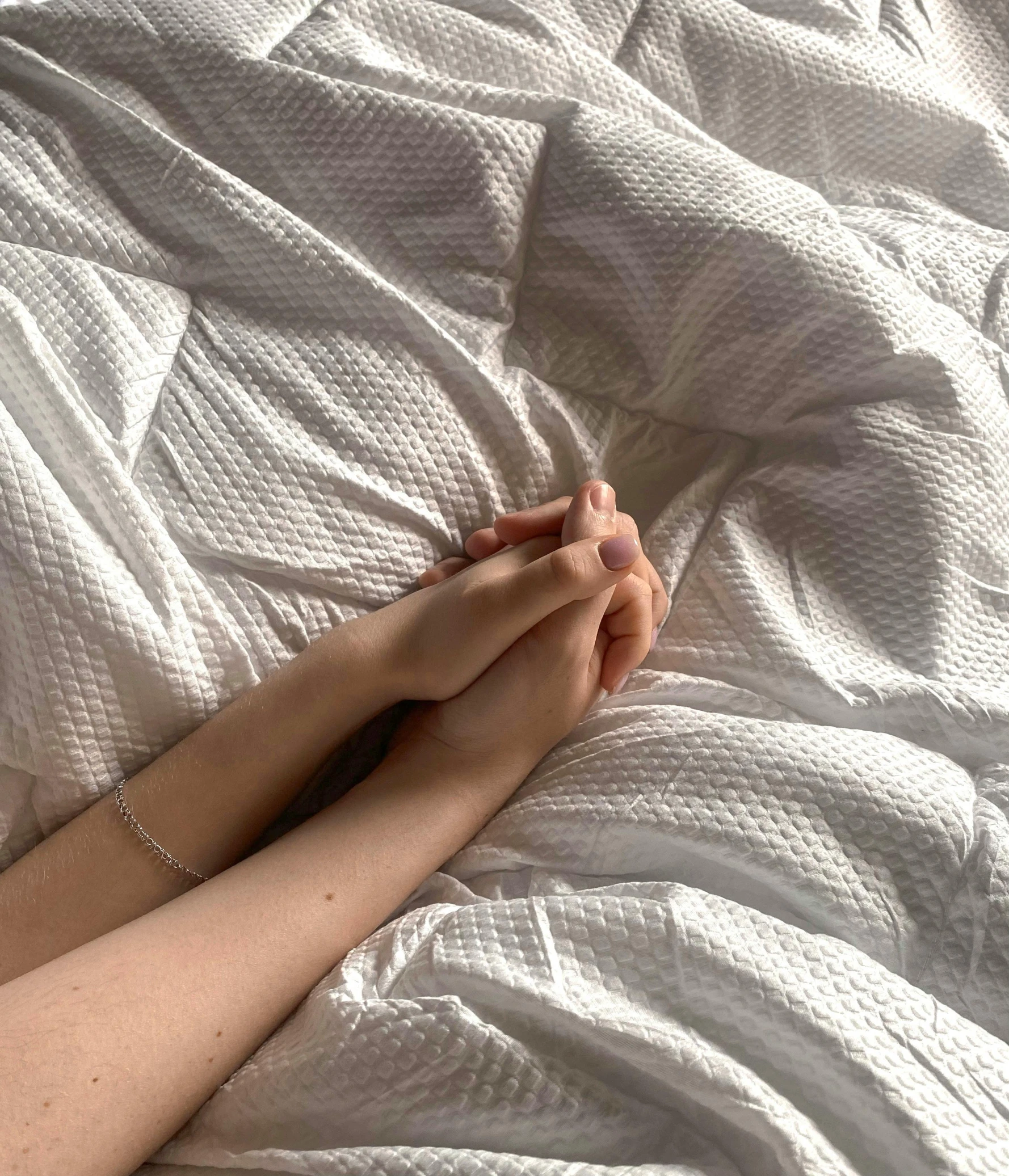 someone is holding their hand on a bed