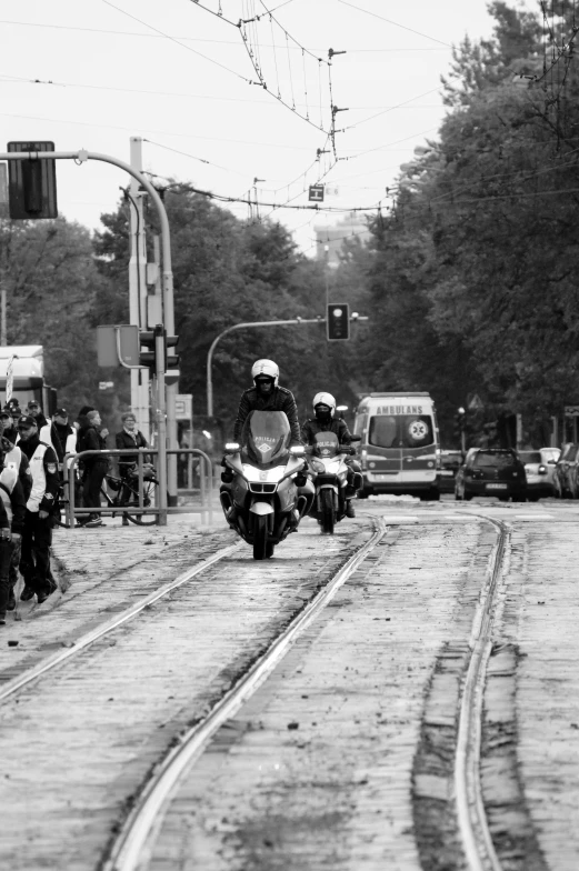 two people are driving motorcycles down the street