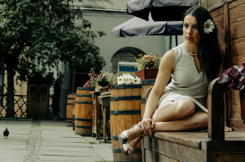 the woman sitting on the wall is wearing a flower in her hair