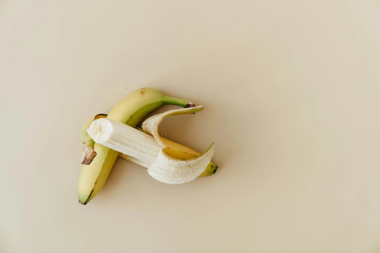 two ripe bananas cut in half next to a green banana