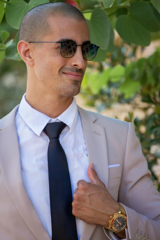 a man with sunglasses wearing a black tie and grey suit