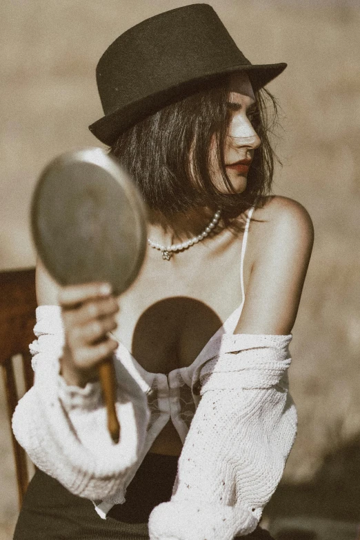 a young woman with a top hat sitting in front of a mirror