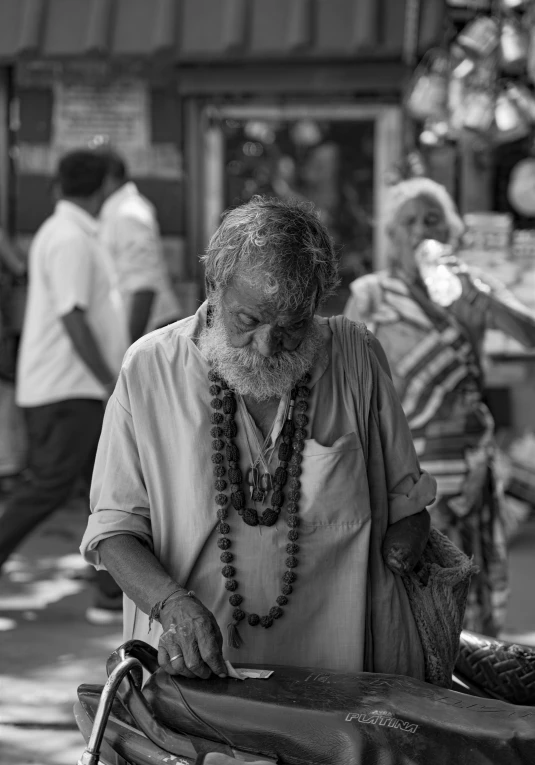 a man with a long beard and an orange strand of beads is making a chain necklace