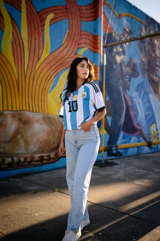 woman standing outside in front of a wall with paintings