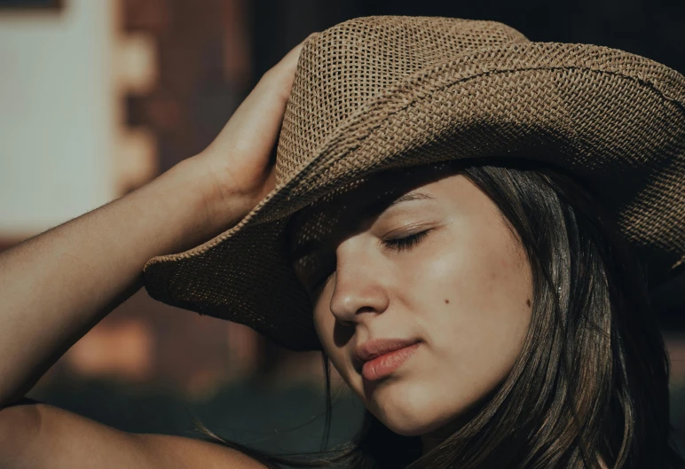 a woman wearing a big brown hat with eyes closed