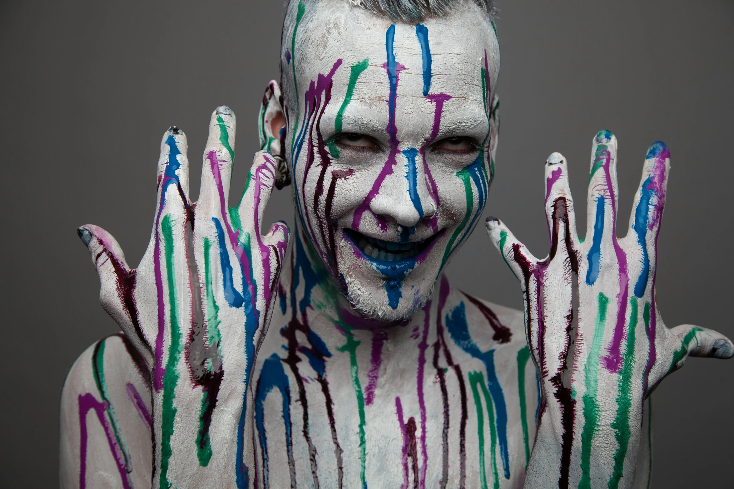 man with hand painted body and hands with purple and blue designs on his chest