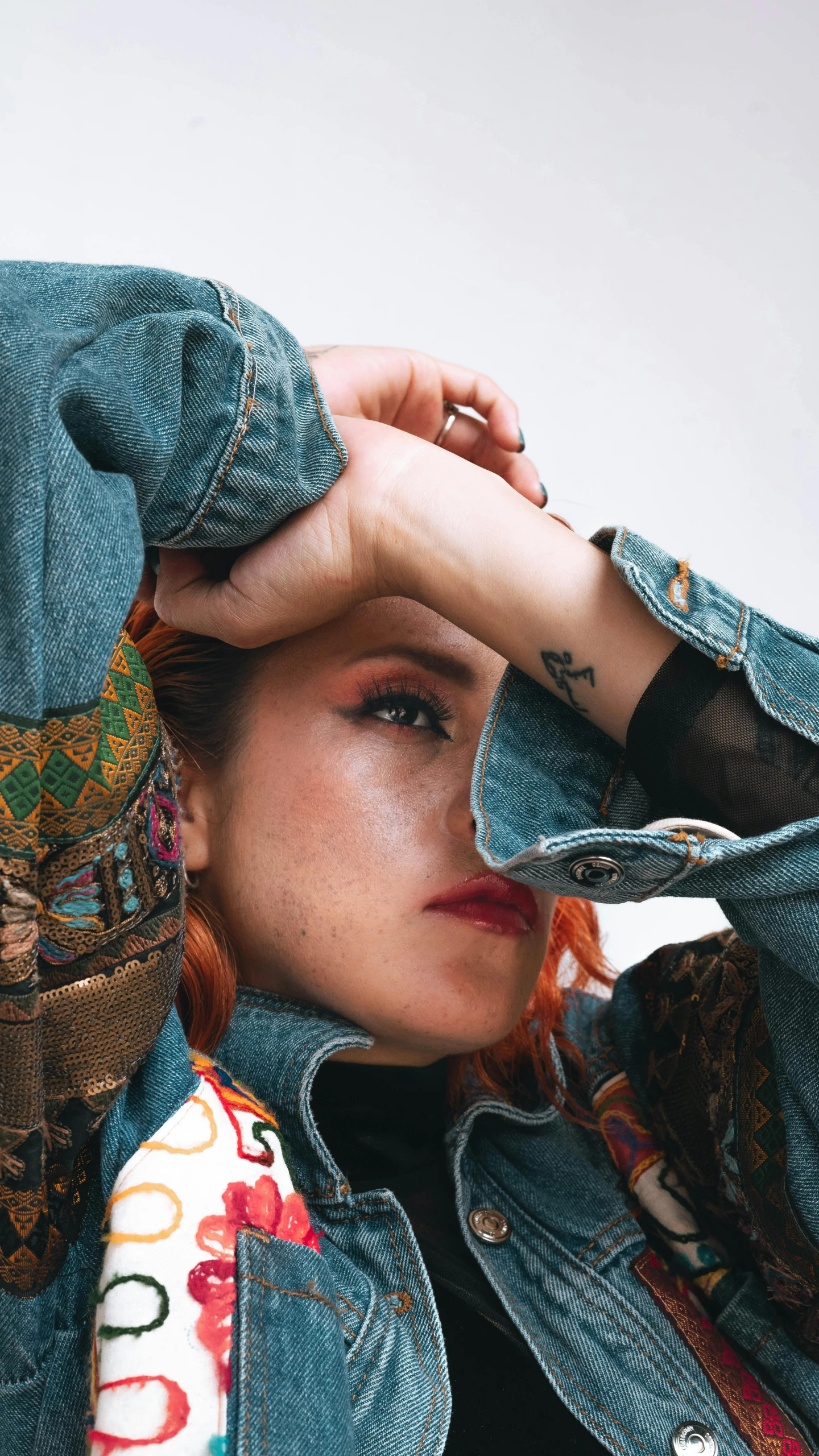 a young woman wearing a jean jacket and a scarf