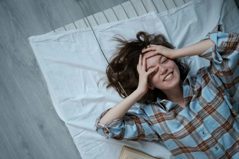 a young woman laying in bed with her hand on her head