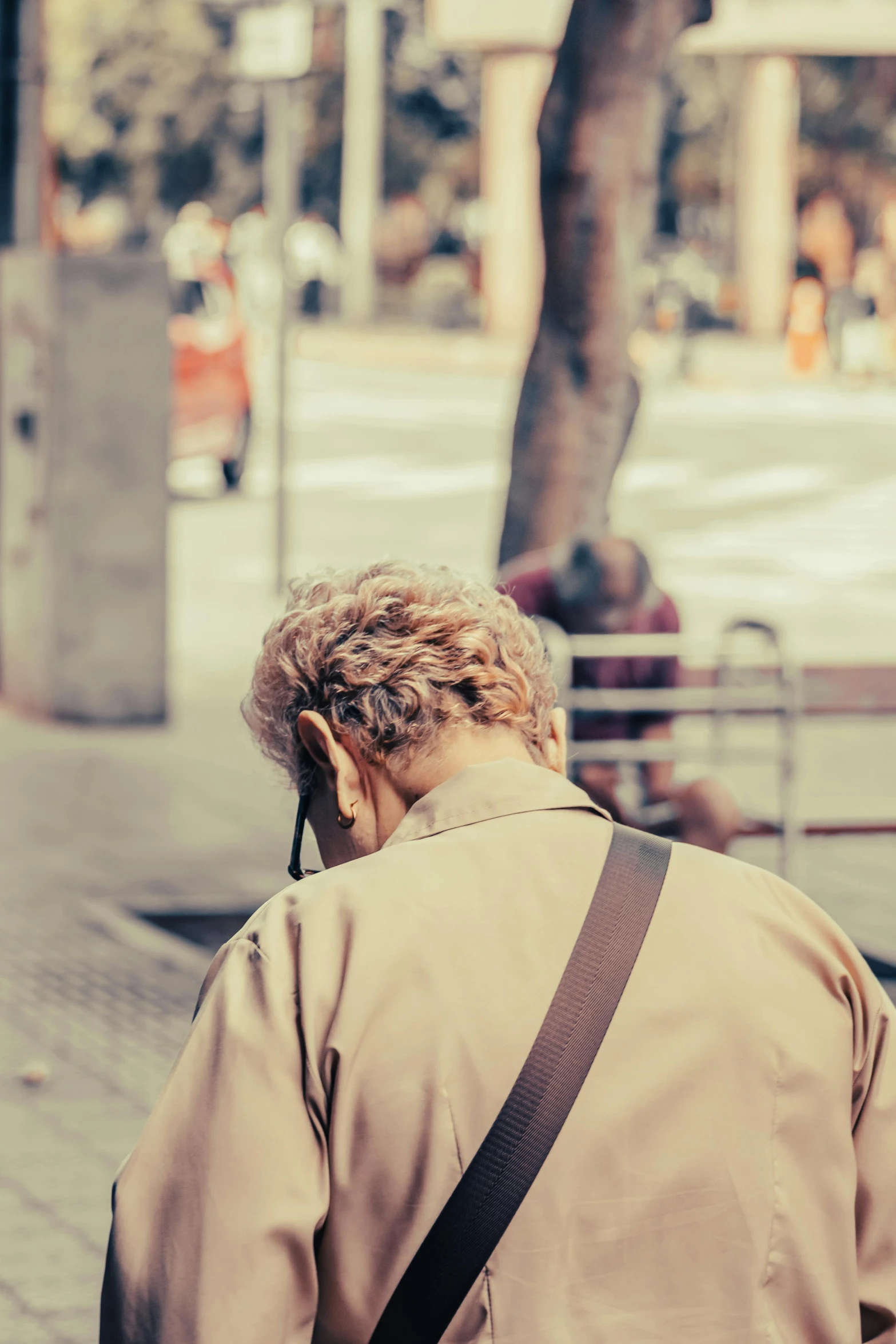 a woman is wearing a tan coat and carrying a cross body bag