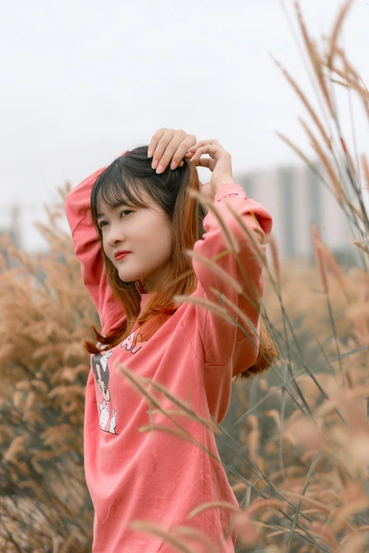 young woman standing in front of a grassy field