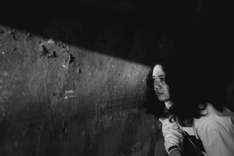 a black and white pograph of a woman holding onto a wall