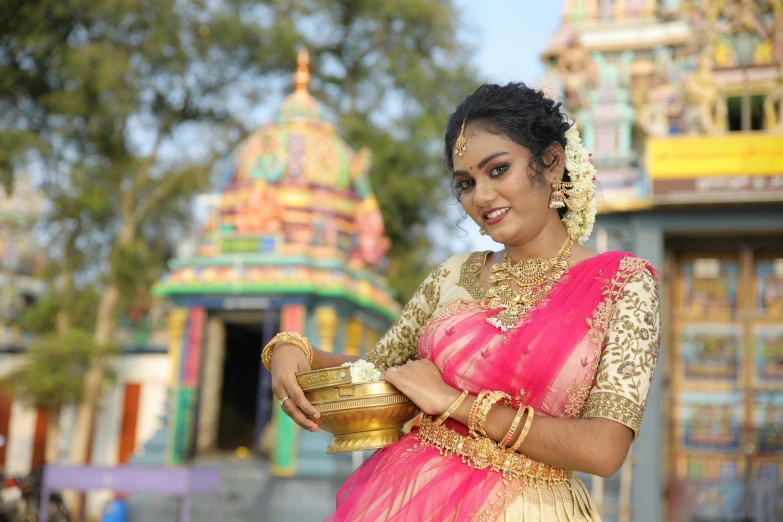 a woman wearing a red and yellow saree holding a plate