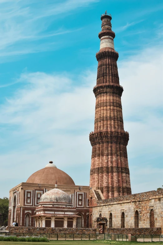 an ancient minaret in the background, behind it a large building with a clock tower