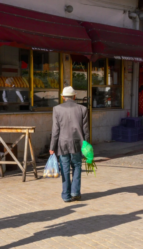 a man walking down the street with a green bag