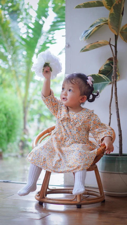 a little girl sitting in a wooden chair