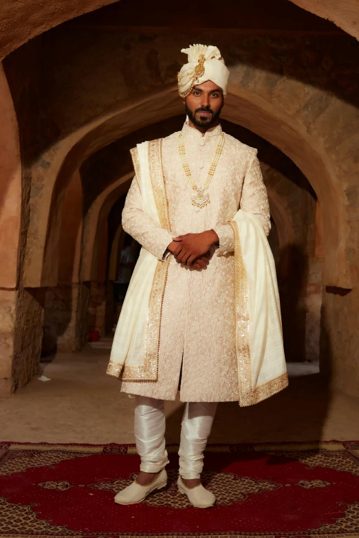 a man in a white sherwa stands with his hands on his hips