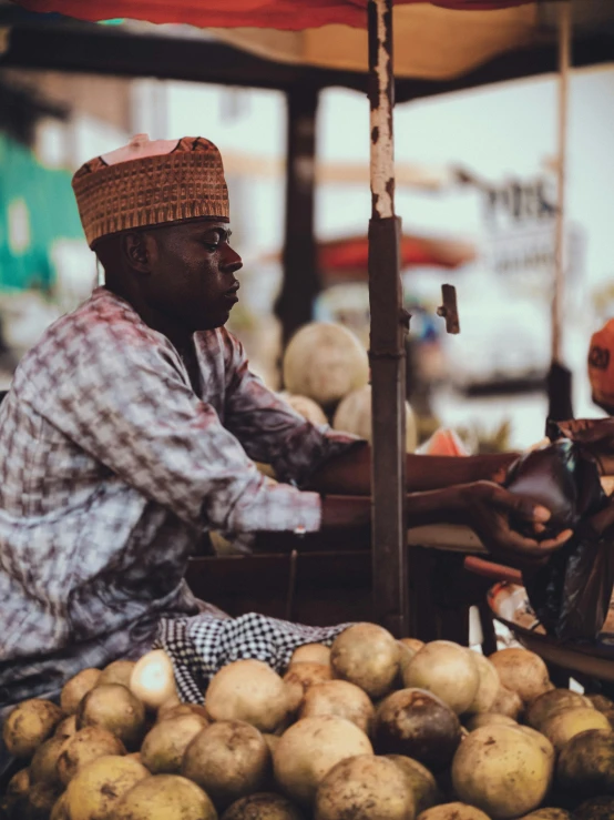 a man sits in front of piles of produce