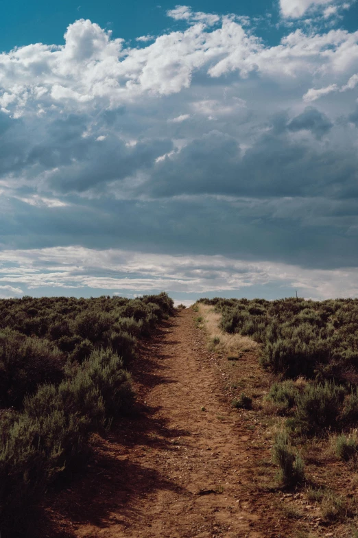 there is an empty dirt road with a sky background