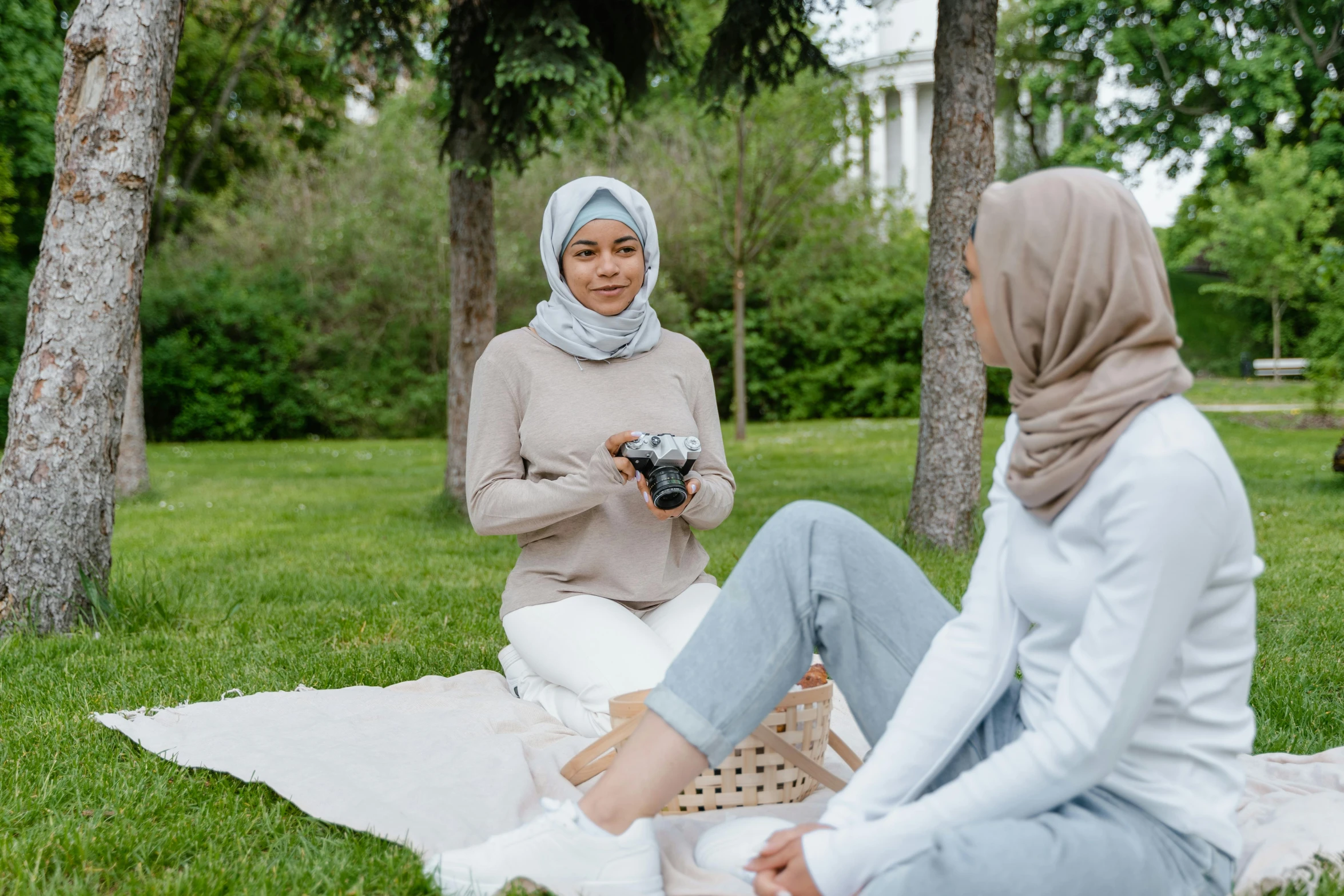 two women sitting on the grass talking and playing games