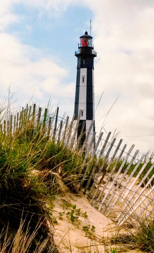 the white and black lighthouse sits in a grassy area