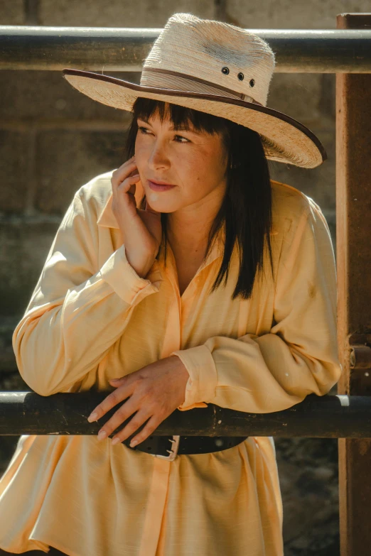 a woman leaning against a rail wearing a hat