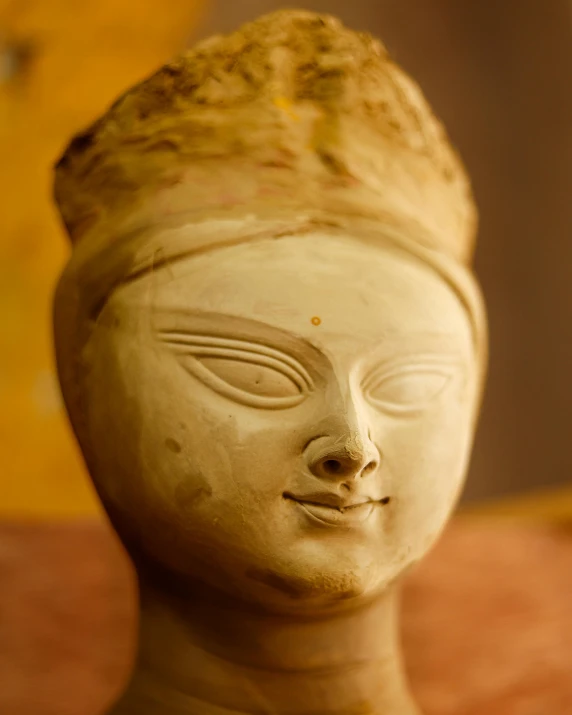 a clay statue of a woman with big eyes