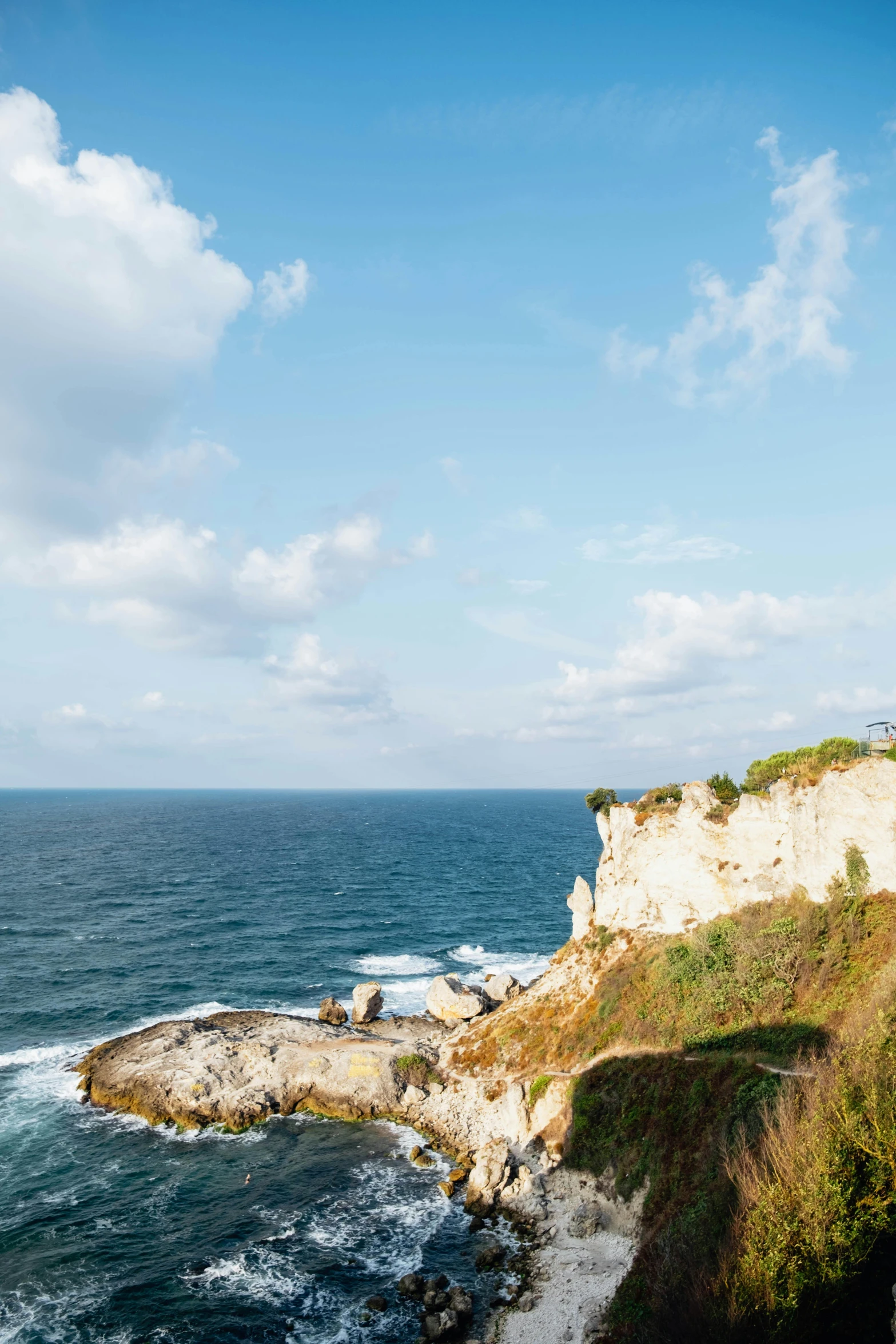 a beach with an ocean cliff and a car driving along it