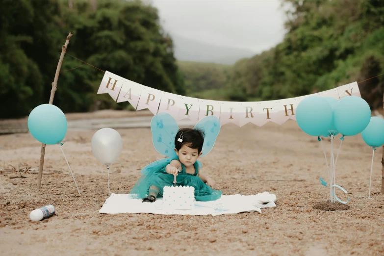 a little girl sitting on the ground with a cake in front of her