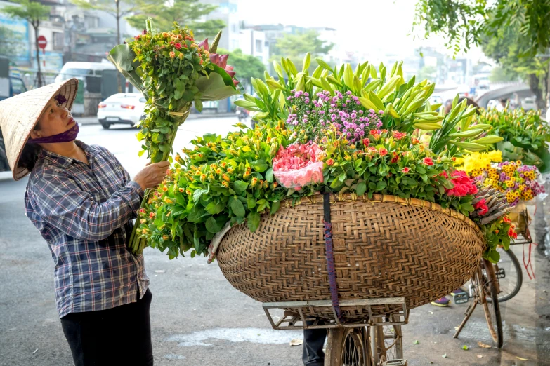 a woman is loading flowers into the back of a bicycle