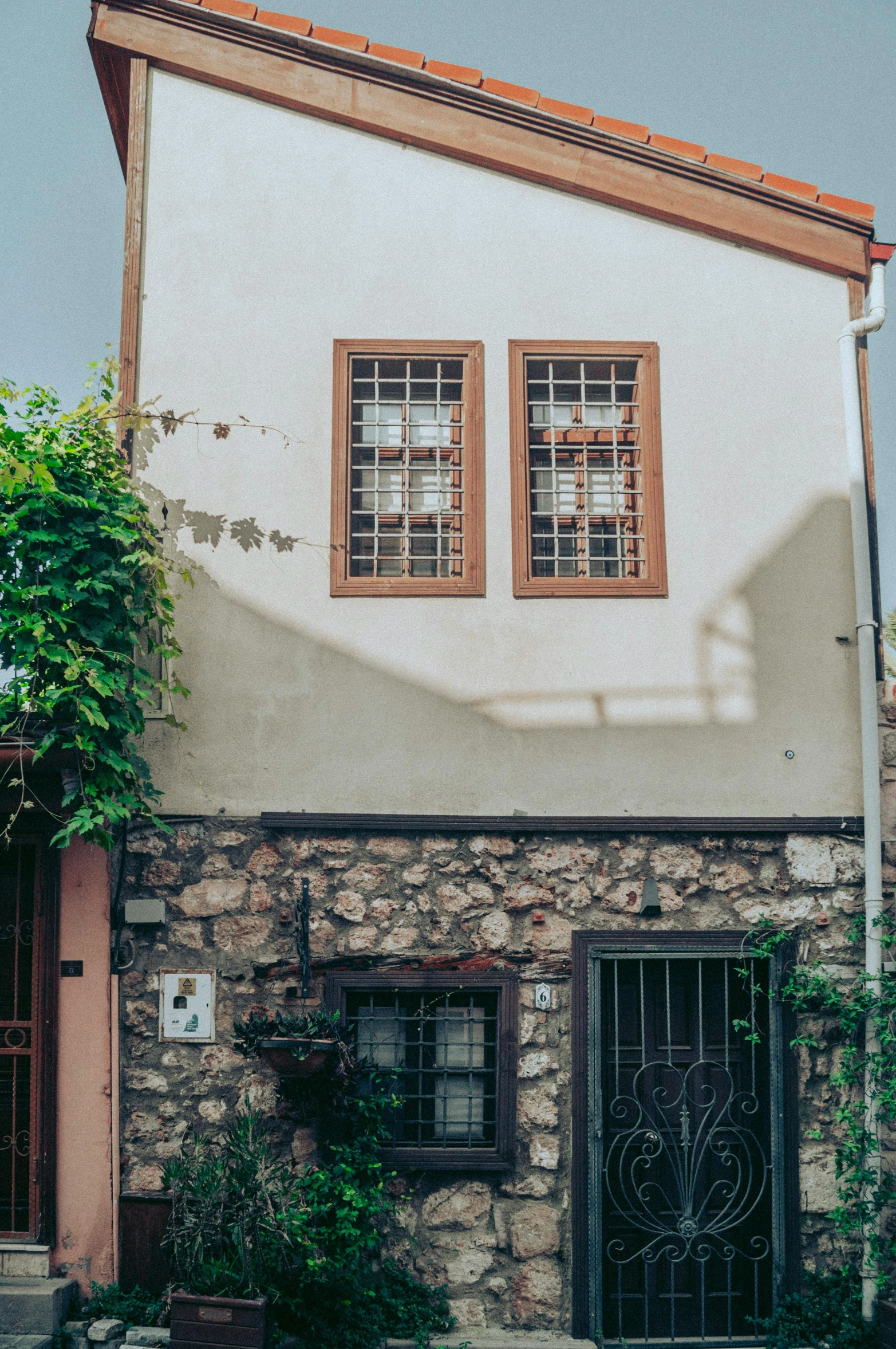 a tall white house with red shutters and a cat on the front steps