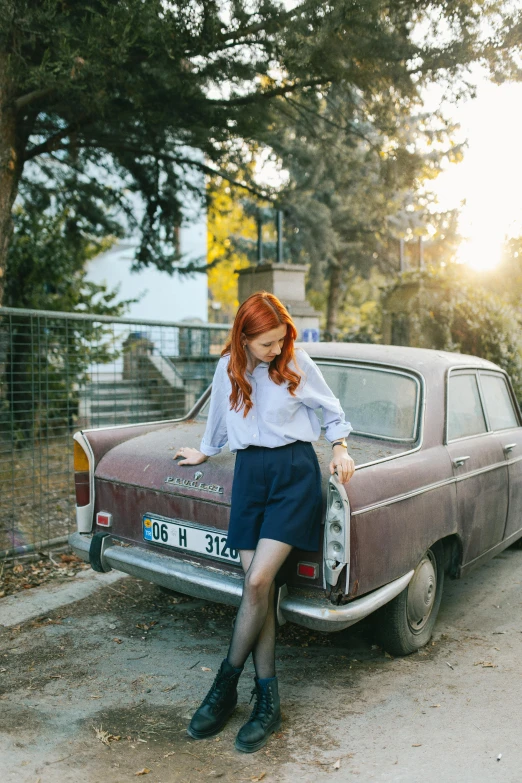 a red haired woman sitting on top of an old car