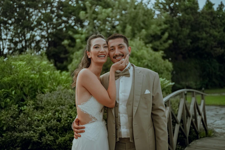 bride and groom standing on a bridge in the woods