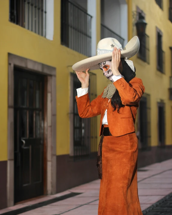 a woman with a mexican hat, jacket and glasses, is dressed in orange