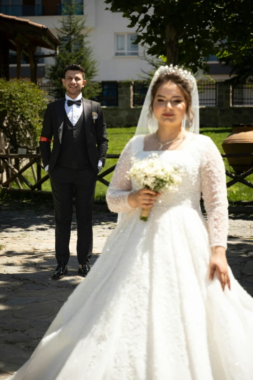 a man is standing next to a woman in a white wedding gown