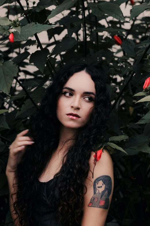 a woman with long black hair standing in front of red roses
