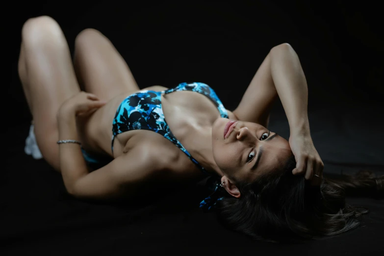 an image of a young woman in blue bikini top lying down