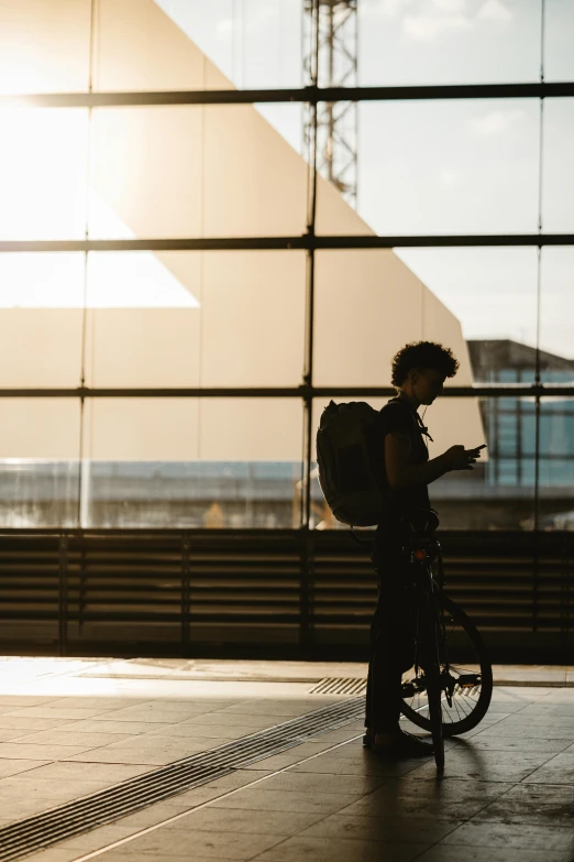 the girl is walking with her bike past a building