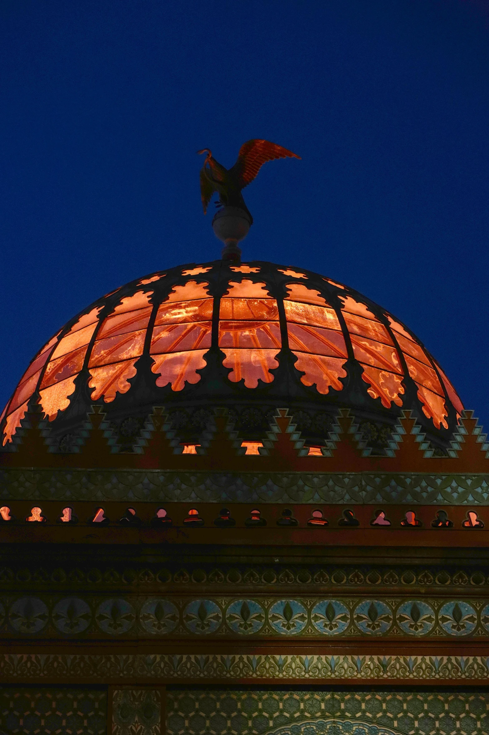 dome of structure illuminated by orange lighting with large winged figure