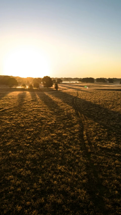 the sun is setting in the distance over a field with a tractor