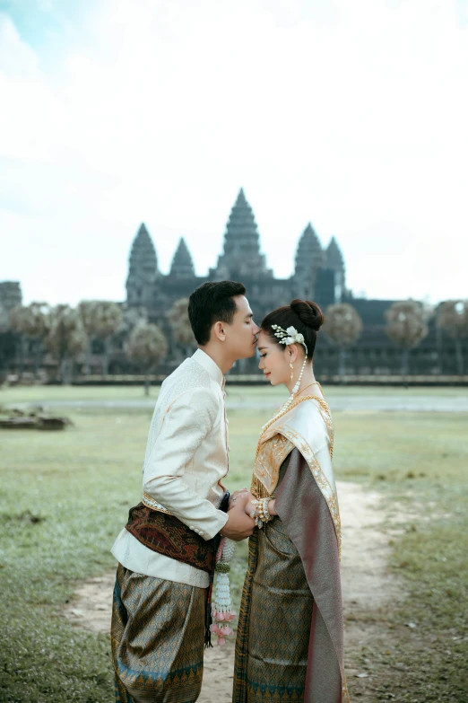 couple in traditional garb pose together outdoors in front of a temple