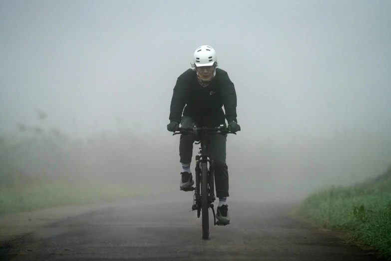 a person is riding their bike down a foggy road