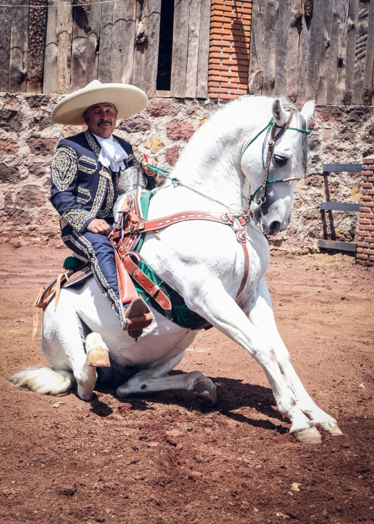 the mexican man is riding his white horse