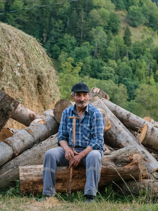 a man in blue shirt sitting on wooden structure next to trees