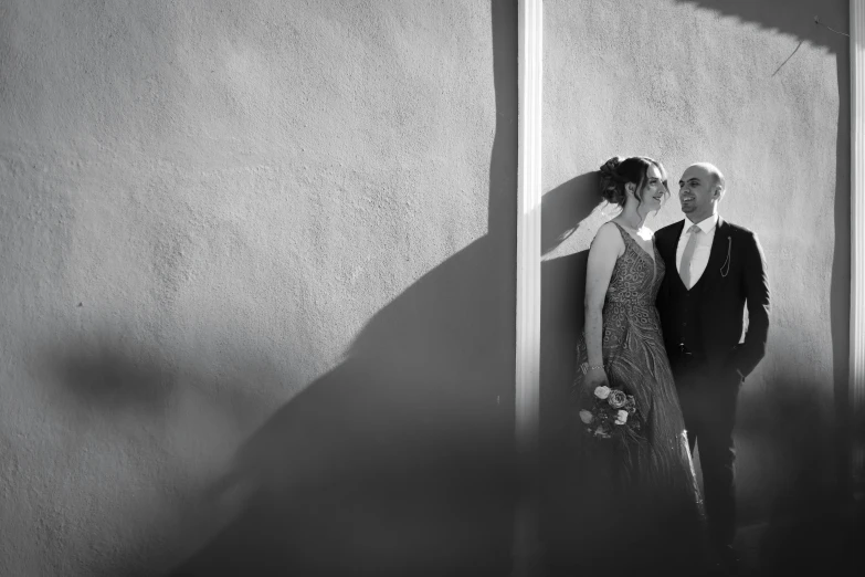 a couple standing near a wall and a window